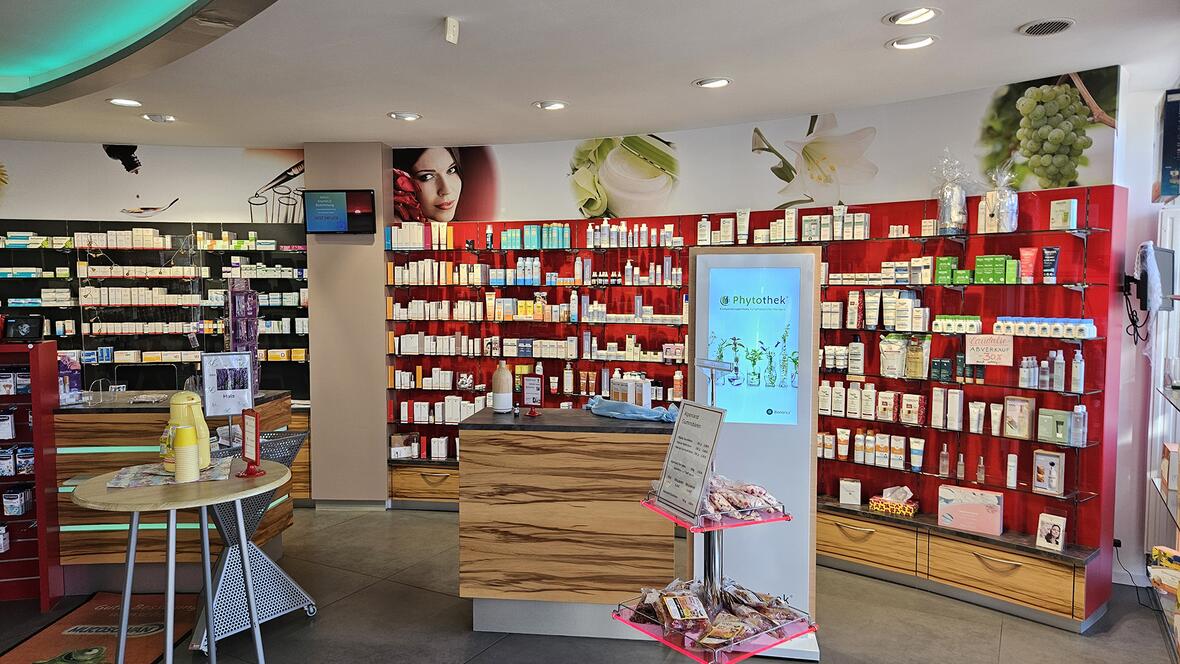 Innensicht der Elisen Apotheke mit Verkaufsregalen voller Pflegeprodukte und einem Empfangstresen.